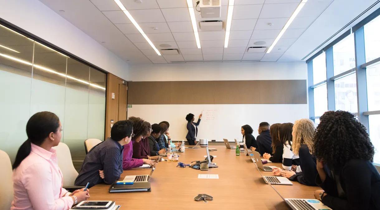 Um grupo diversificado de profissionais envolvidos na discussão em torno de uma grande mesa de conferências em uma sala de reuniões moderna.