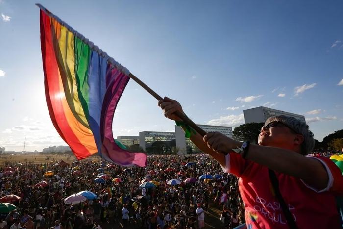 Homem segura uma bandeira do arco-íris durante a parada do orgulho no Rio de Janeiro, Brasil.